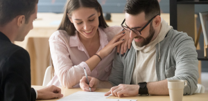 Smiling couple signing a contract with a professional advisor, symbolizing trust and positive customer experience.